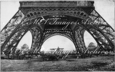 Les travaux du champ de Mars à travers les arceaux de la tour Eiffel. エッフェル塔のアーチ部から覗いたシャン・ド・マルス会場の建設工事